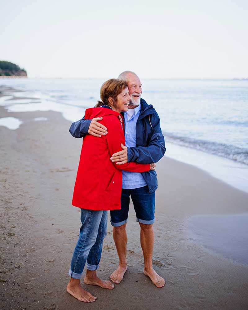 11Heureux couple de personnes âgées amoureux embrassant en marchant sur la plage de sable